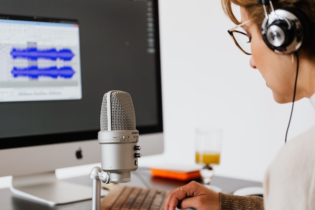 Eine Frau von hinten über die Schulter fotografiert beim Podcast aufnehmen.