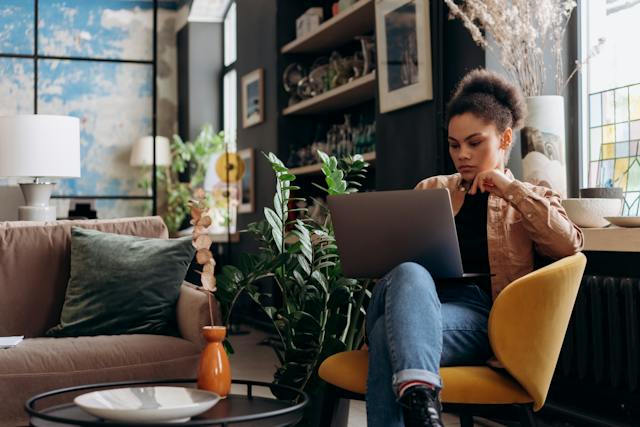 Eine Frau sitz in einem Sessel und arbeitet im Online-Coworking an ihrem Business.