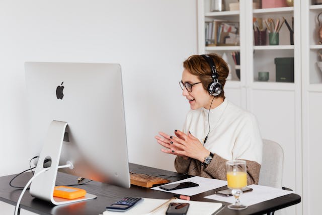 Eine Unternehmerin tauscht sitzt am Schreibtisch und tauscht sich per Videocall mit gleichgesinnten Frauen aus.